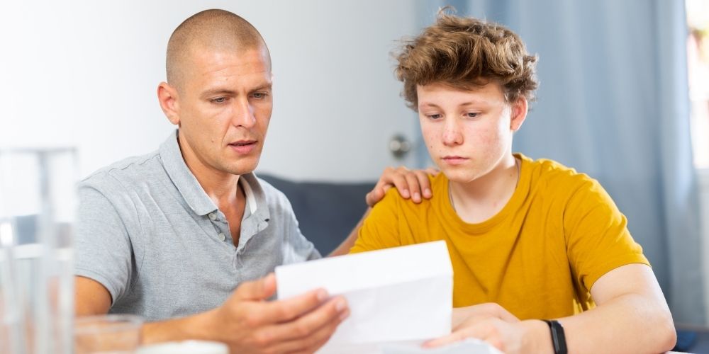 Dad teaching his teen son about how to manage money.
